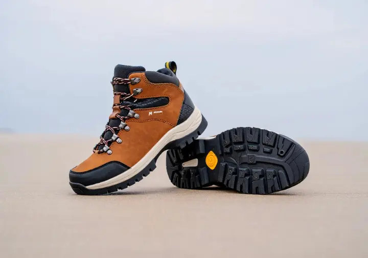 Close-up of a women's hiking boot, clearly showing its upper, midsole, and outsole, explaining the anatomy of a world-class hiking boot.