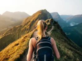 A hiker wearing a daypack stands at a trail junction in the mountains, choosing between a sunny ridge and a misty valley, symbolizing the selection of the right rucksack for any trail.