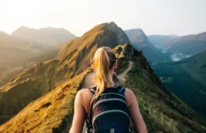 The Right Rucksack for Any Trail: A Hiker’s Daypack Guide A hiker wearing a daypack stands at a trail junction in the mountains, choosing between a sunny ridge and a misty valley, symbolizing the selection of the right rucksack for any trail.
