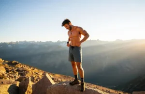 Men’s Hiking Shorts: A Data-Backed Analysis A hiker stands on a mountain peak, looking down at his technical men's hiking shorts, representing a data-backed analysis of the best gear for the trail.