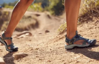 Women’s Hiking Sandals: Zero vs. High Drop? A female hiker compares a zero-drop hiking sandal on one foot with a high-drop hiking sandal on the other, illustrating the choice between footwear philosophies for women.