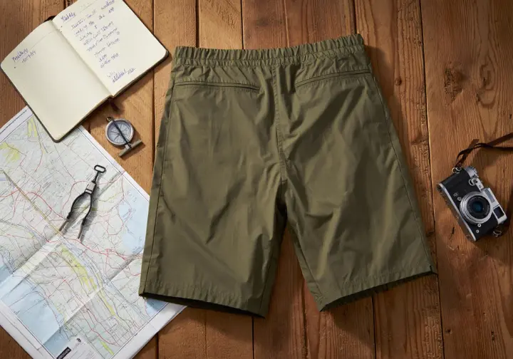 A flat lay showing men's hiking shorts alongside a map, compass, and notebook, illustrating the bridge between theory and our testing methodology.