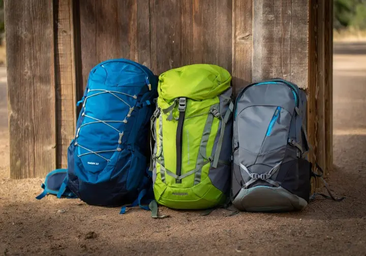Three of the best day hiking rucksacks of 2025 arranged neatly at a trailhead, showcasing top picks for different hiking styles.