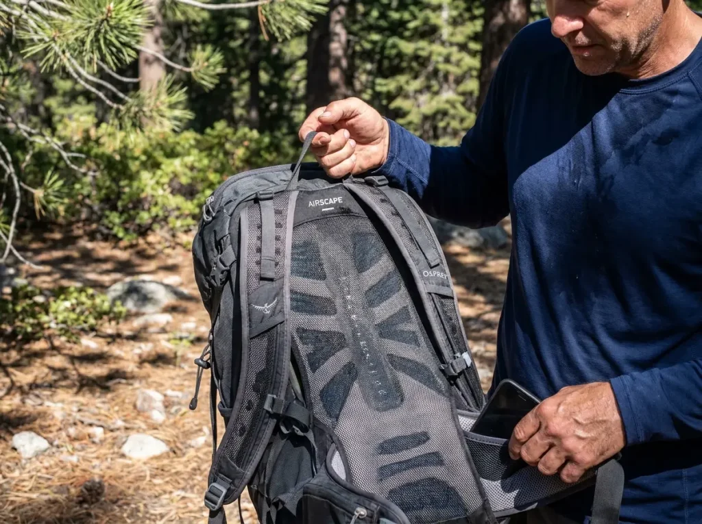 Sweat-damp ventilated back panel of a daypack as a hiker shrugs it off at a shaded rest stop
