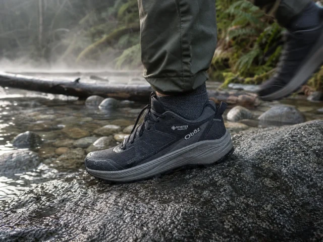 0-mens-waterproof-shoes-oboz-katabatic-wet-granite Men's waterproof hiking shoe on wet granite beside a shallow trail creek at dawn