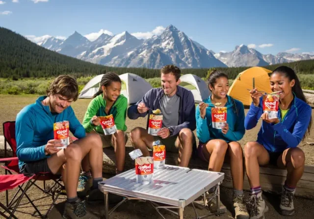 Diverse hikers enjoying Good To-Go gluten-free, vegan, and nut-free meals at a backcountry campsite, highlighting safe and enjoyable trail food.