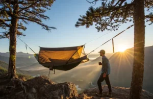 The 5 Best Hammock Tents for Hiking: Field-Tested A hiker enjoys a morning coffee next to their field-tested hammock tent, set up on a mountain overlook at sunrise.