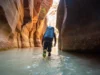 Hiking Water Shoes for The Narrows & Beyond: A Guide A prepared hiker wearing specialized hiking water shoes wades through the Virgin River in the magnificent slot canyon of The Narrows, Zion National Park.
