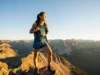 The Pro Hiker’s Guide to Women’s Hiking Shorts A female hiker wearing functional hiking shorts stands on a mountain summit at golden hour, looking out over a vast mountain range.