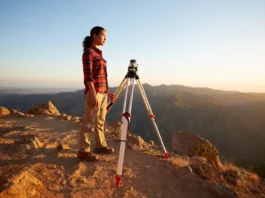A land surveyor in steel toe hiking boots stands with her professional equipment on a scenic mountain trail, embodying the focus of this field-tested buyer's guide.