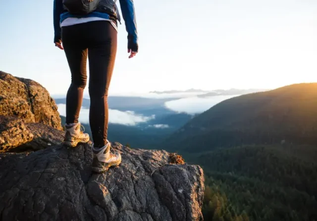 A woman hiker in waterproof shoes stands on a misty mountain trail, representing a field-tested guide to women's waterproof hiking footwear.