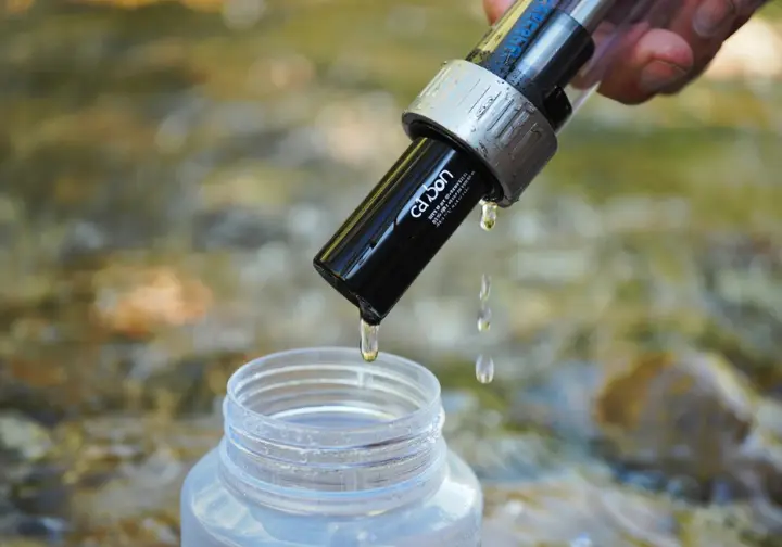 A hiking water filter with activated charcoal removing chemicals from water, emphasizing its role as a chemical guardian in activated charcoal camping.
