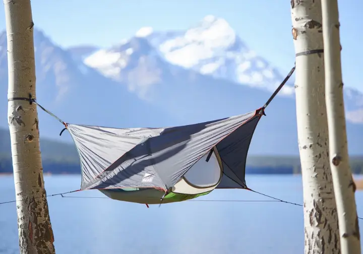 A top-rated all-in-one hammock tent, one of our top picks, pitched perfectly beside a serene alpine lake.