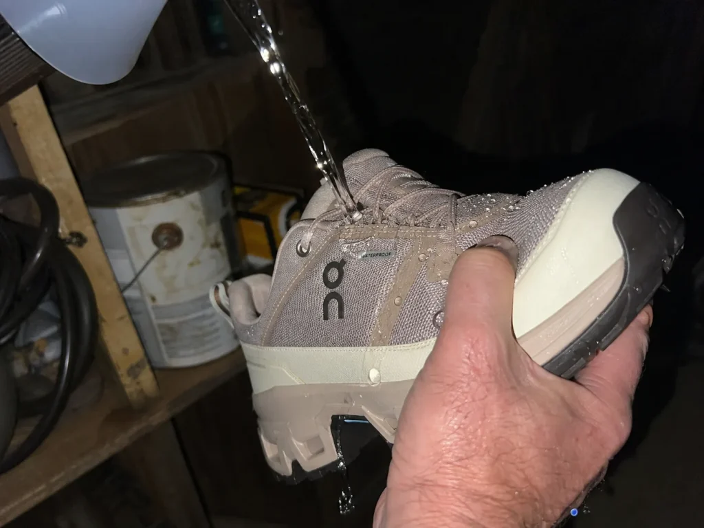 Water beading on the upper of a waterproof hiking shoe held under a garage light