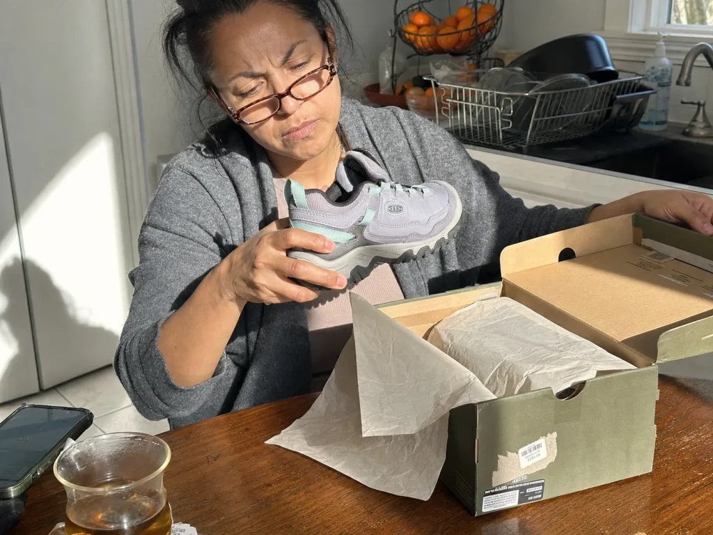 New waterproof hiking shoe on a kitchen table with the box, someone checking the label