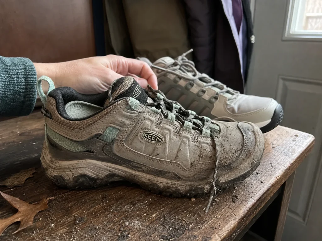 Two pairs of women's waterproof hiking shoes side by side on a bench, worn and newer
