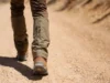 The Hiker’s Guide to Gaiters: How to Choose & Use A hiker on a dusty trail wears mid-height gaiters, illustrating their function in preventing debris from entering boots, for a guide on hiking with gaiters.