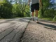 Best Sneaker for Walking: 10-Mile Trail-Edge Tested A full-body shot of a person walking on a path that transitions from city pavement to a gravel trail, testing sneakers.