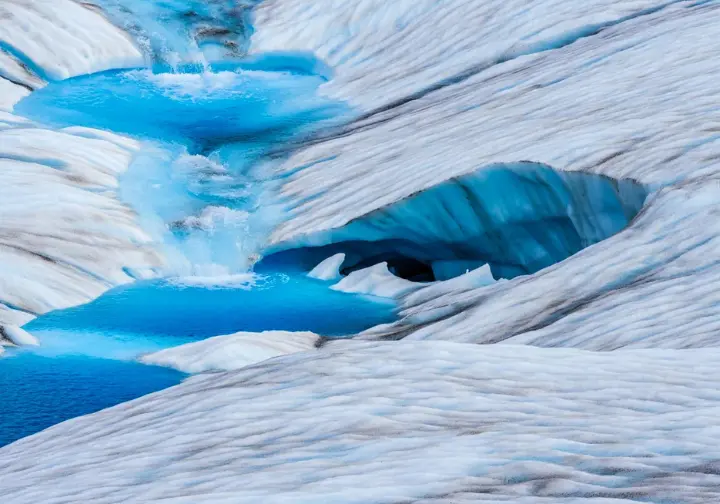 Split image showing Matanuska Glacier in summer with blue meltwater pools and in winter with ice caves, illustrating the seasonal experience of a Matanuska Glacier walk.