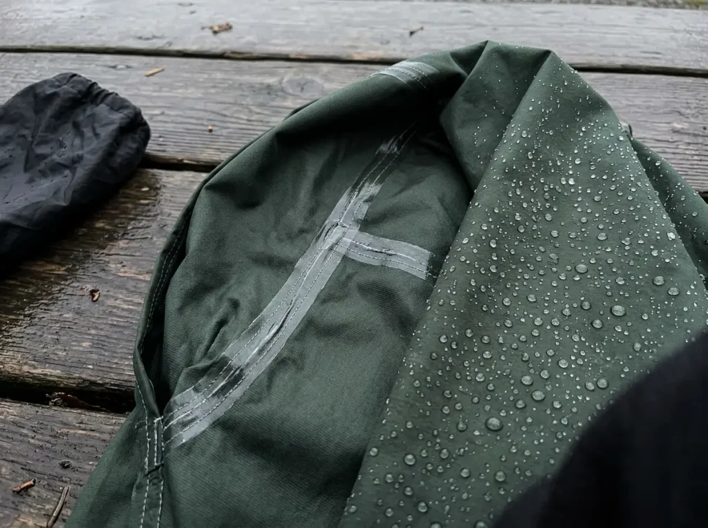 Close view of taped seams and beading water on a waterproof rain jacket shell