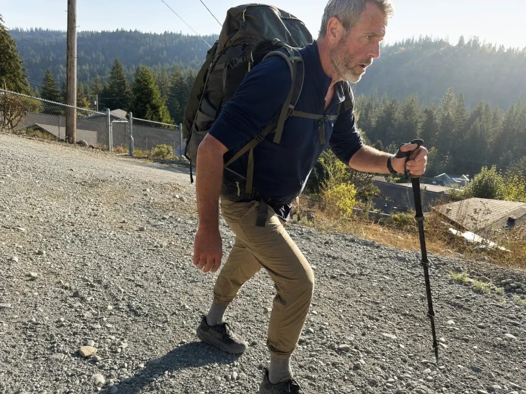 Hiker walking a steep local hill with a loaded pack to break in backpacking shoes