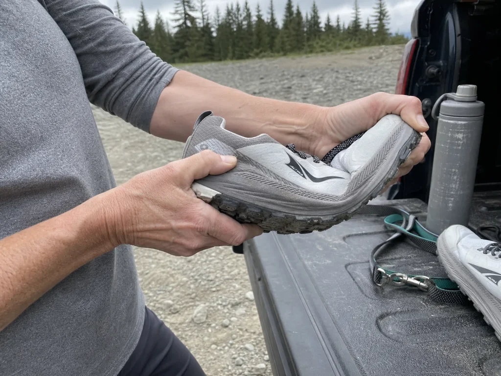 Hands twisting an Altra Lone Peak 9 to test torsional stiffness of the midsole