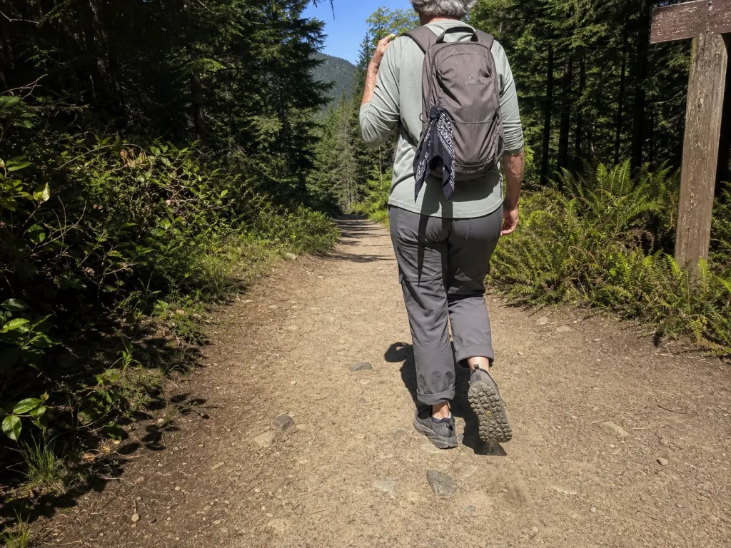 Day hiker in low-cut trail sneakers walking a maintained dirt trail at midday