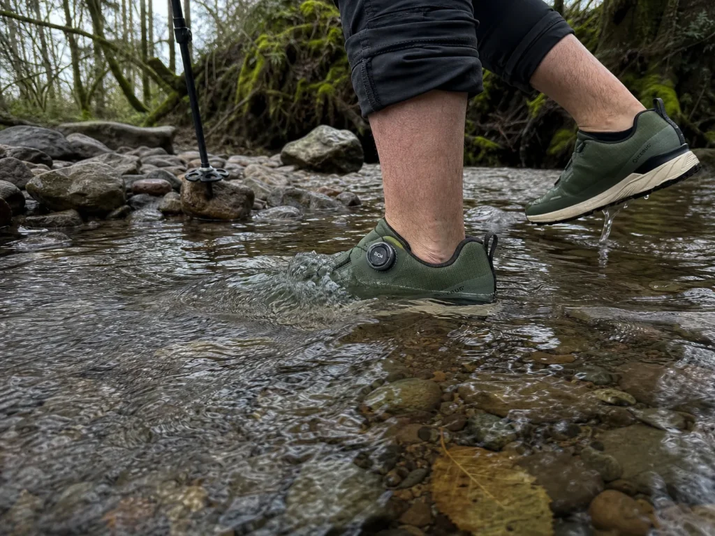 Hiker stepping through an ankle-deep stream crossing in waterproof trail sneakers