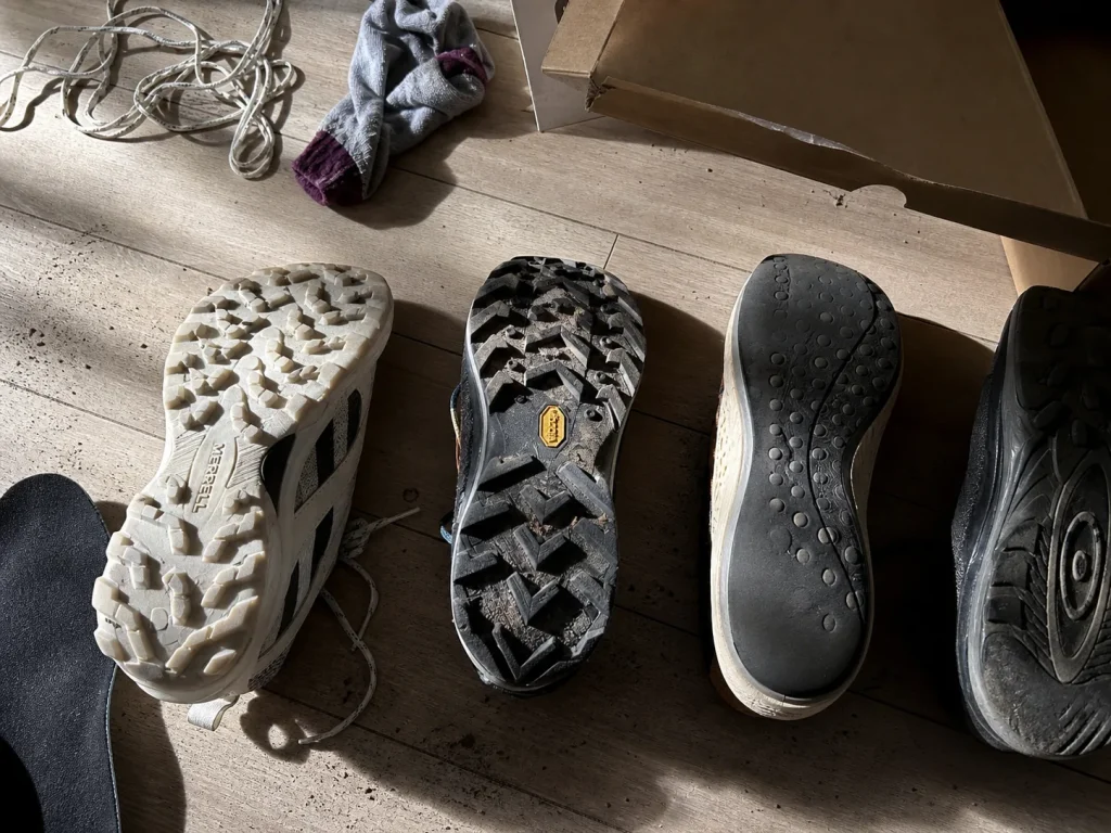 Low-cut hiking sneakers lined up sole-up on a floor for outsole comparison