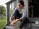 Best Walking Footwear for Women Who Also Hike Woman loosening her walking shoes on the back steps after a morning dog loop