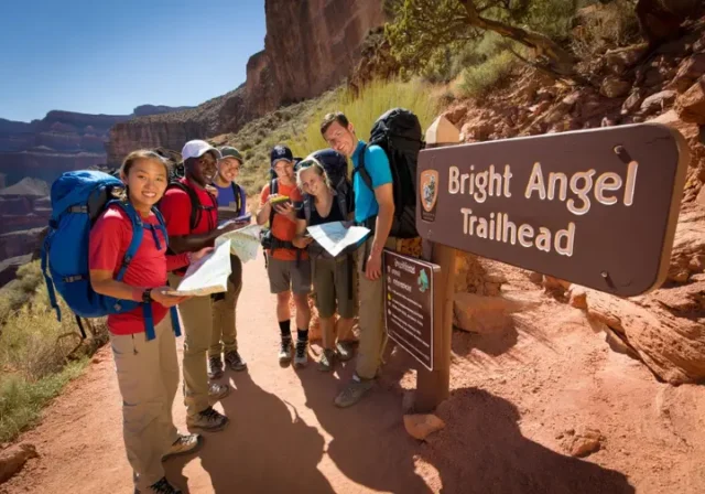 Hikers preparing at the Bright Angel Trailhead, Grand Canyon, with informational signs and the trail visible, illustrating a guide to parking and shuttles.