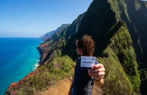 Kalalau Trail Permits: A Step-by-Step Strategy A hiker on a dramatic overlook of the Na Pali Coast with a printed Kalalau Trail permit in hand, symbolizing a successful permit strategy.