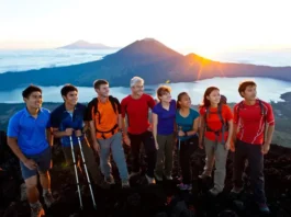 Diverse hikers on the summit of Mount Batur at sunrise, looking at the panoramic view, illustrating key information before booking a Mt. Batur trek.
