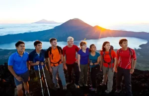 Mt. Batur Trek: What to Know Before You Book a Tour Diverse hikers on the summit of Mount Batur at sunrise, looking at the panoramic view, illustrating key information before booking a Mt. Batur trek.