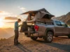 Pickup Bed Tents for Hikers: 2025 Field-Tested Guide A hiker in full outdoor gear stands next to their pickup truck, which has a bed tent set up at a mountain trailhead at sunset.