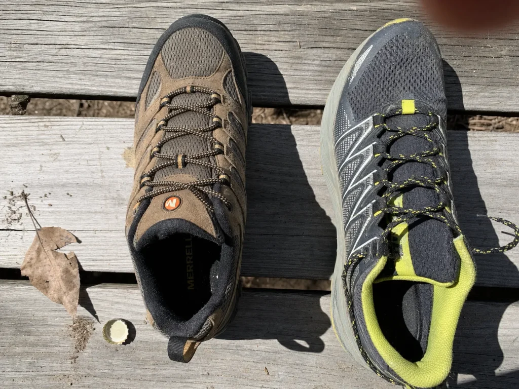 Two low-cut hiking shoes side by side on a wood bench showing silhouette and material differences