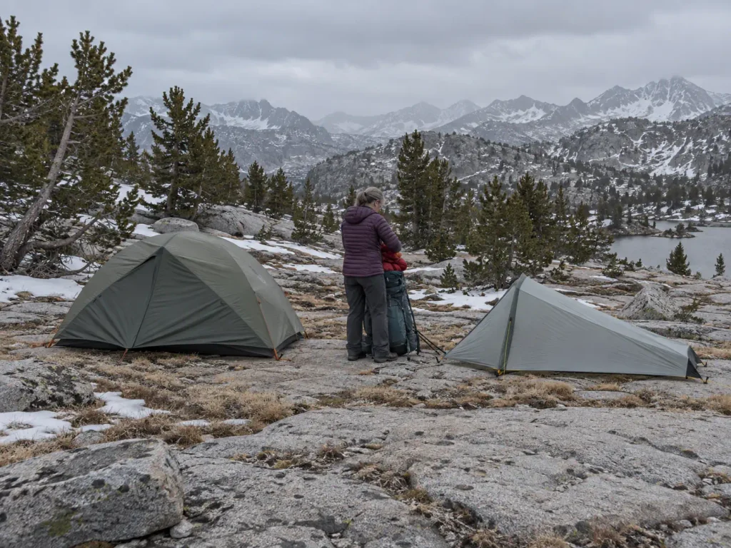 Two backpacking shelters of different types pitched at a shoulder-season Sierra Nevada camp