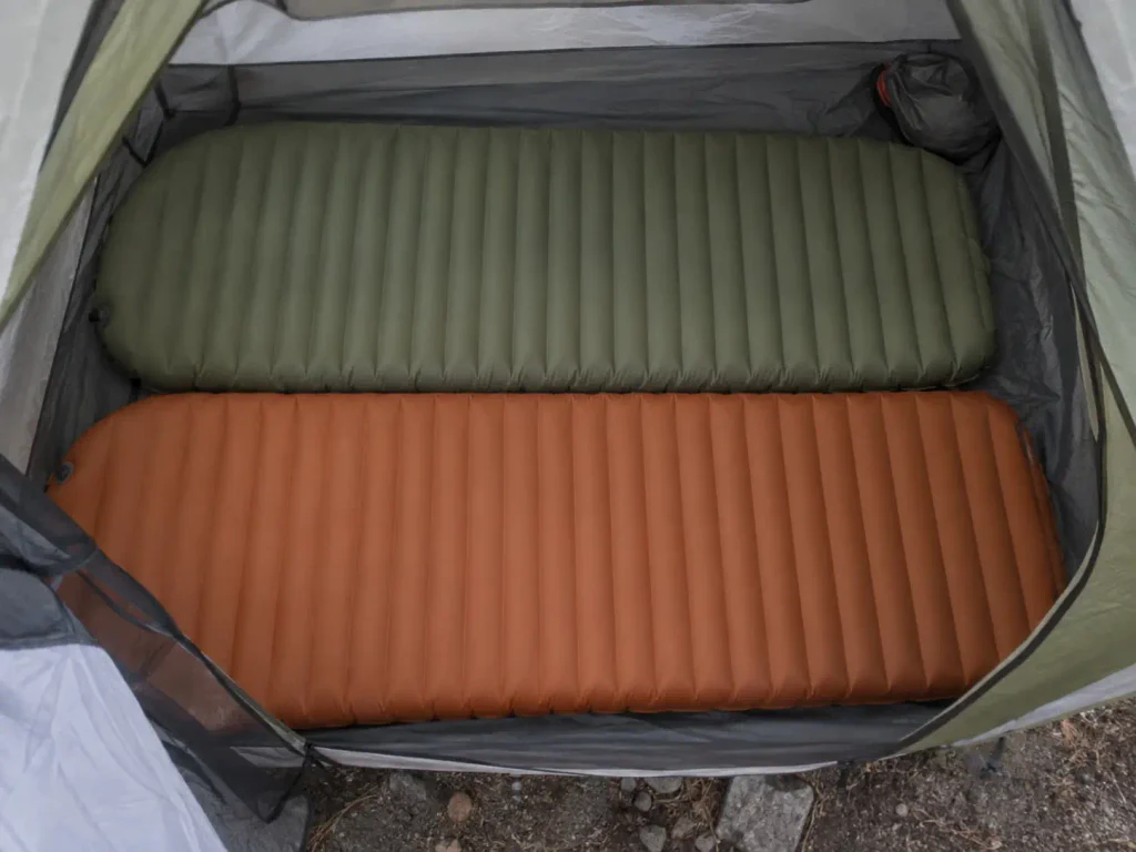 Two sleeping pads side by side filling the floor of a two-person backpacking tent