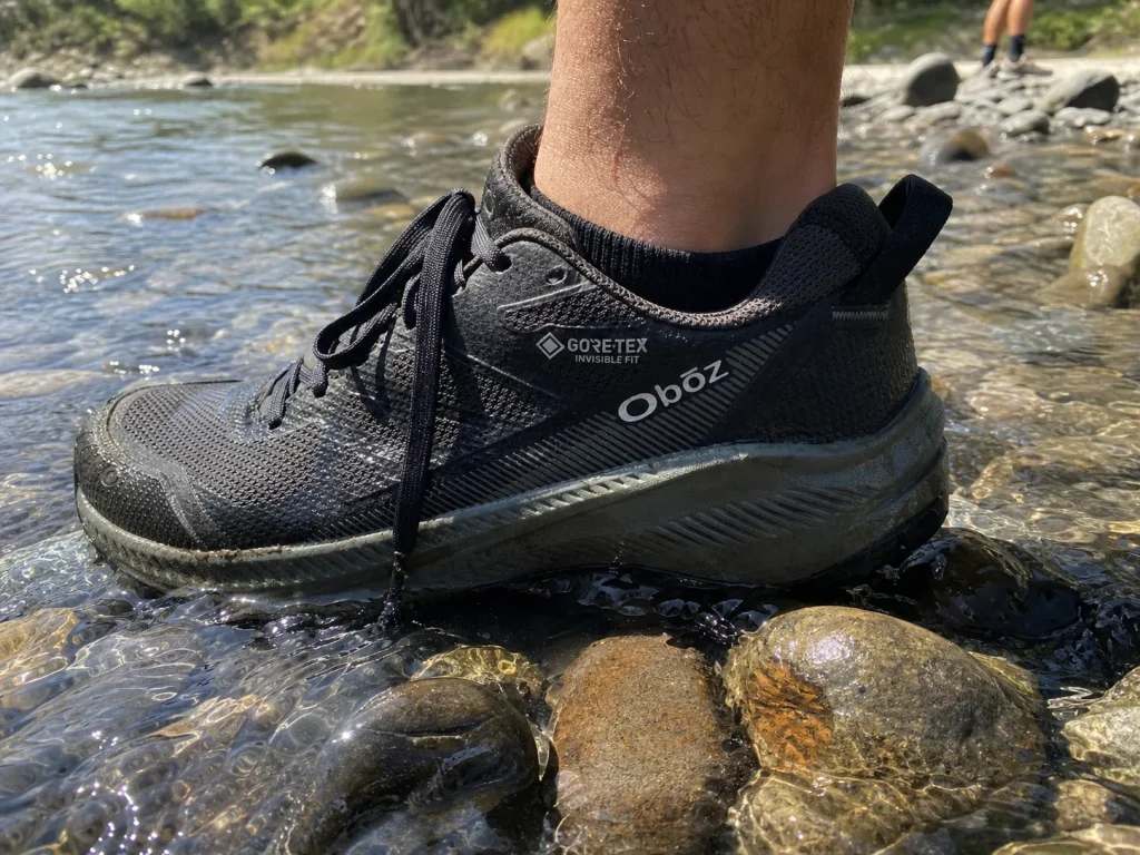 A waterproof low-cut hiking shoe stepping through the shallow edge of a rocky creek crossing