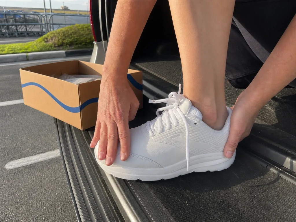 Hands checking the forefoot width of a wide walking shoe against a foot