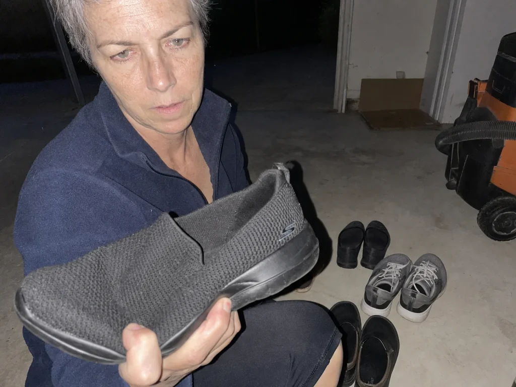 Thumb pressing into the midsole of a worn walking shoe to test dead cushioning