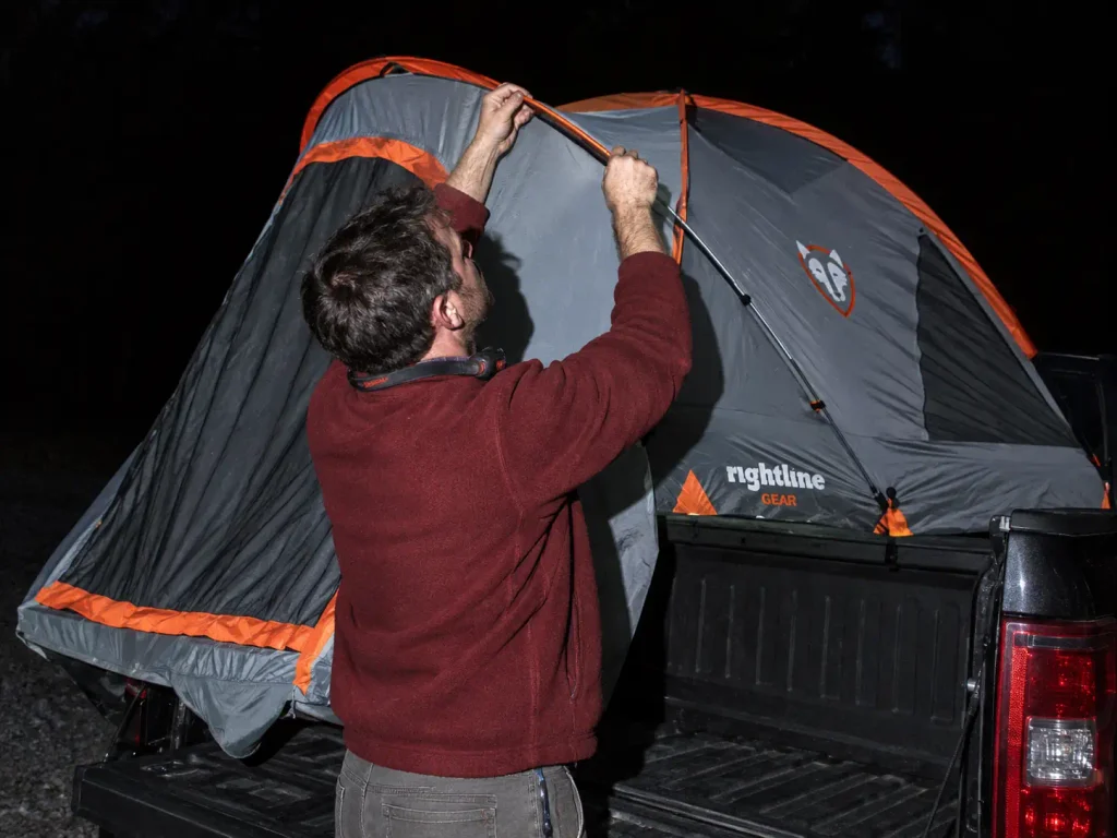 Rightline Gear floorless truck bed tent being set up at dusk at a gravel campsite
