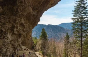 Alum Cave Trail: To the Bluffs & Beyond to Mt. LeConte A hiker stands at the base of the towering Alum Cave Bluffs, showcasing the geological feature and the starting point for a hike to Mt. LeConte.
