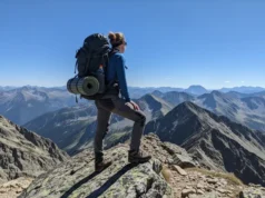 Female Hiking Pants: The Definitive Expedition-Ready Edit A full-body shot of a female hiker in expedition-ready hiking pants and gear, standing on a mountain summit looking at the view.