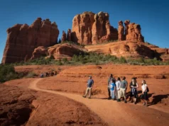 Hiking Bell Rock: Trails, Vortex & a Complete Guide A diverse group of hikers on a trail with Bell Rock and Courthouse Butte in the background, representing the varied experiences and comprehensive guide to hiking Bell Rock.