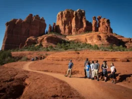 A diverse group of hikers on a trail with Bell Rock and Courthouse Butte in the background, representing the varied experiences and comprehensive guide to hiking Bell Rock.