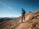 Trekking Shoe Ratings: The Definitive Performance Guide A hiker in a full-body shot walks along a sunny mountain trail, wearing sturdy trekking shoes and a backpack.