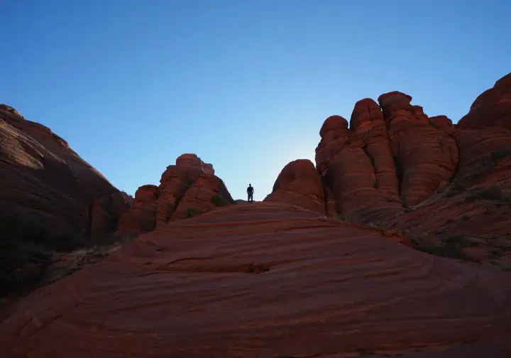 A lone hiker stands amidst the vast, serene red rock canyons of Zion's Kolob Canyons district, showcasing the park's quieter corners.