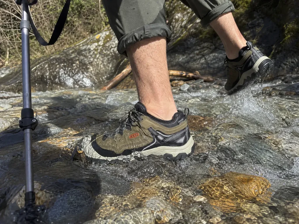 Waterproof trekking shoe mid-stream crossing with water above the collar