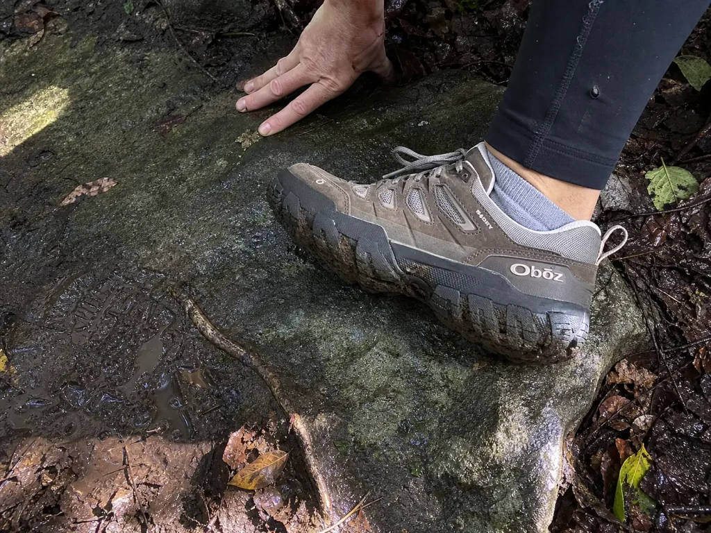 Close look at hiking shoe outsole lugs gripping wet rock and packed mud